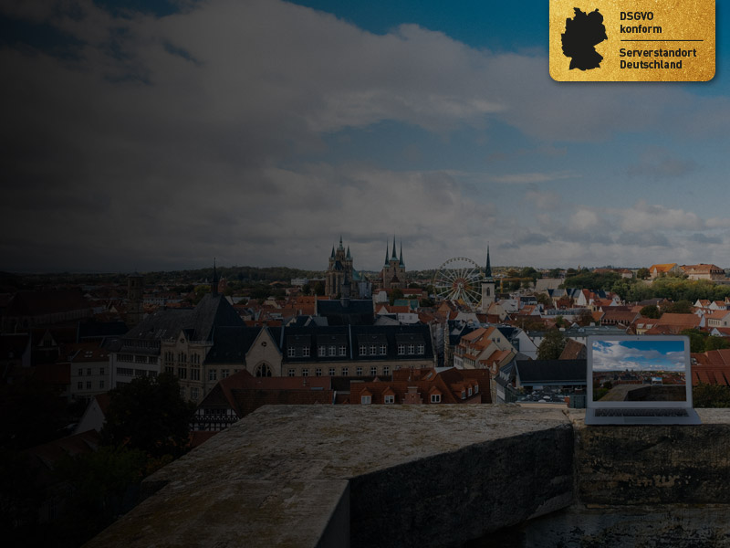 Webhosting Pakete aus Deutschland - dargestellt durch einen Laptop, der auf einer Mauer mit Blick über den Dom in Erfurt steht