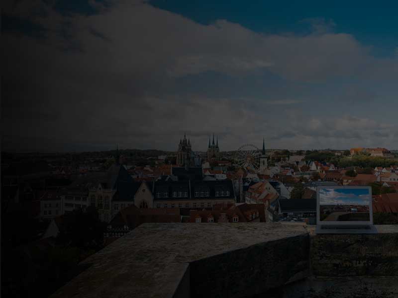 Web hosting packages from Germany - represented by a laptop standing on a wall overlooking the Erfurt Cathedral.