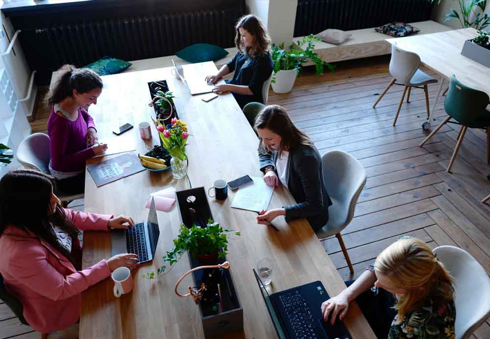 Employees sit together at one table and work