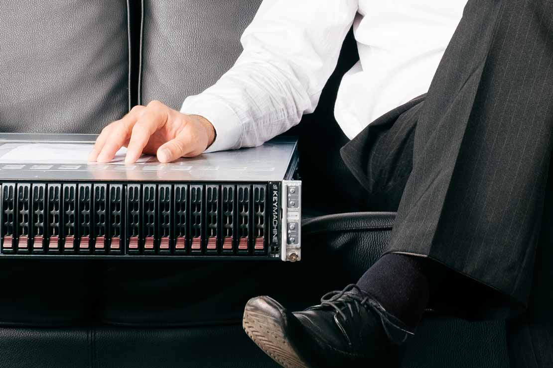 A businessman sits on a couch - next to him a server