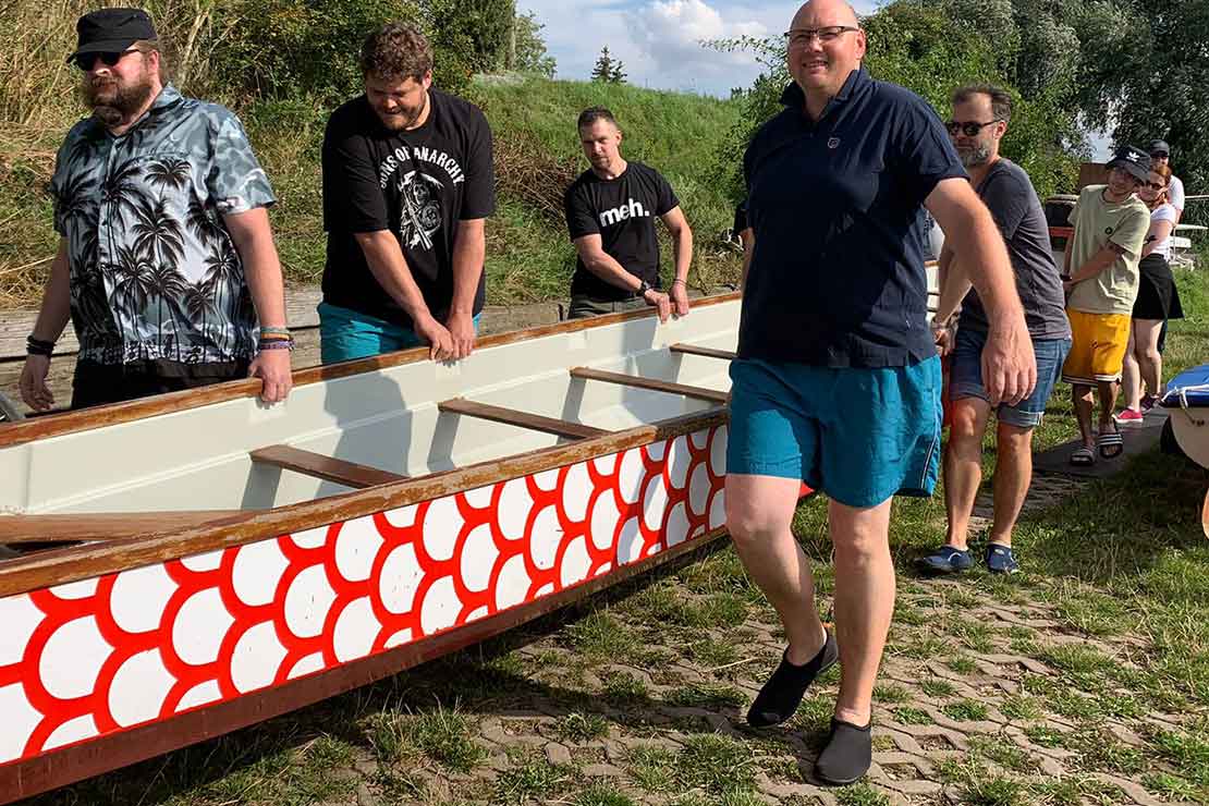Keyweb Mitarbeiter und Auszubildende tragen in Erfurt ein Boot in einen See